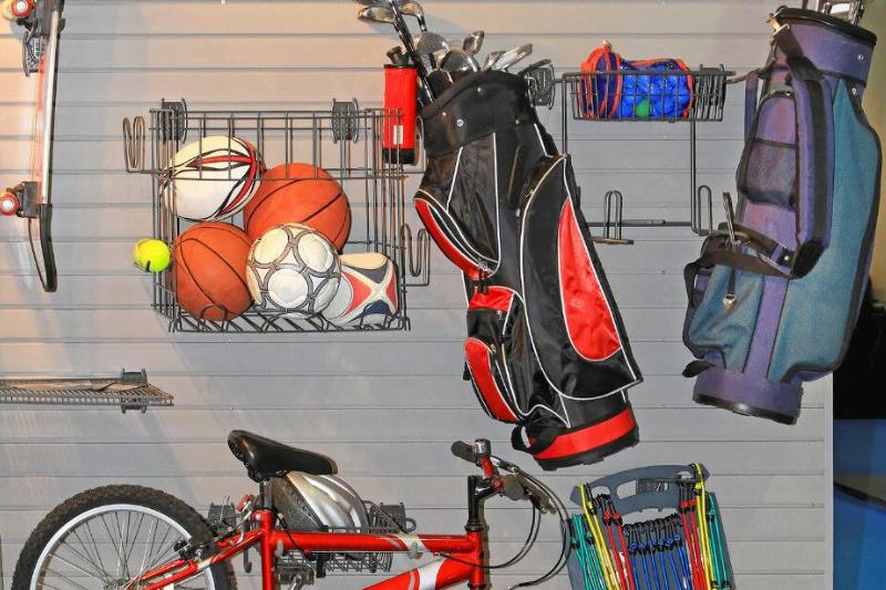 Golf clubs and other summer toys on the wall of a garage.