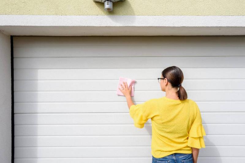 Woman cleaning outside of garage door.