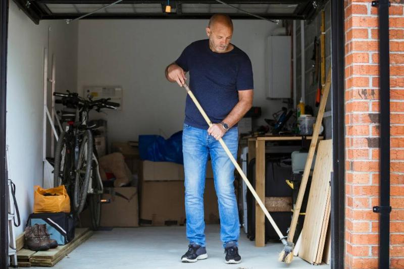 Man sweeping out garage.