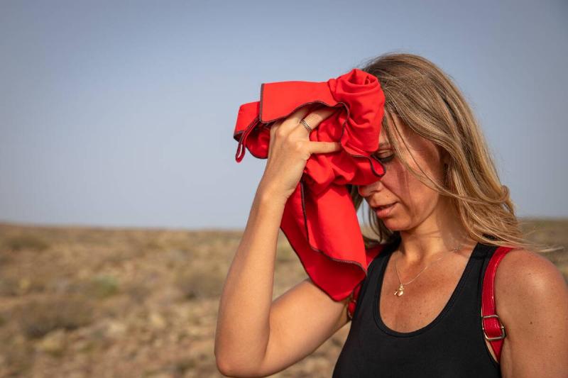 Woman putting wet bandana on her face.