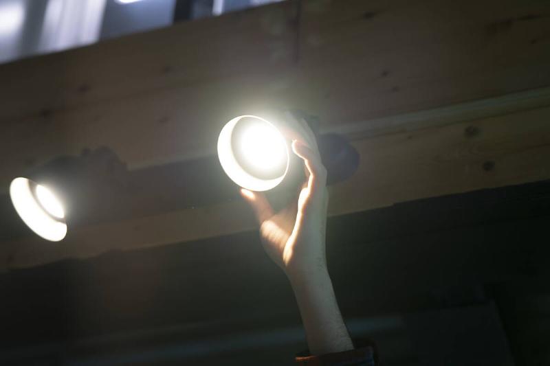 Hand readjusting outdoor light bulb. 