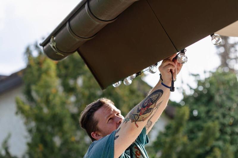 Man readjusting light on house.