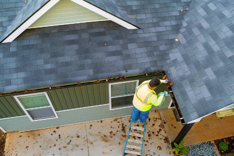 Man clearing leaves out of gutter.