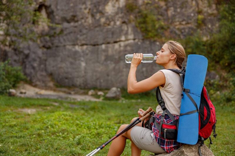 Woman drinking water from bottle on hike. 