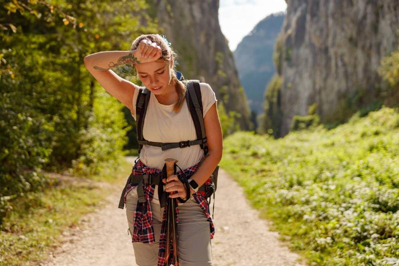 Woman tired, wiping her brow on a hike. 