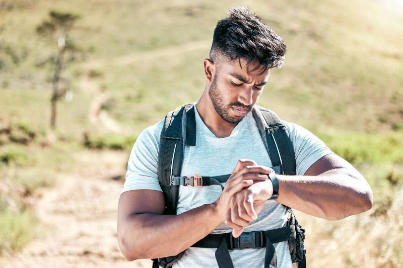 Man checking his watch on a hike. 
