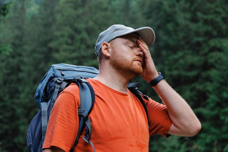 Male hiker putting hand on face.