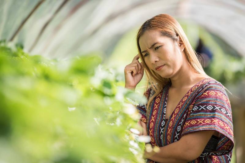 Confused woman looking at plants.