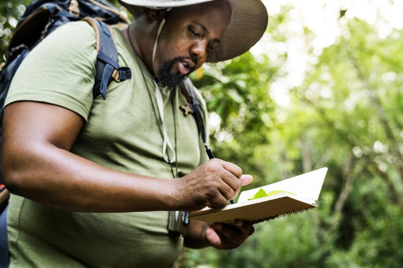 Male hiker making notes in notepad.