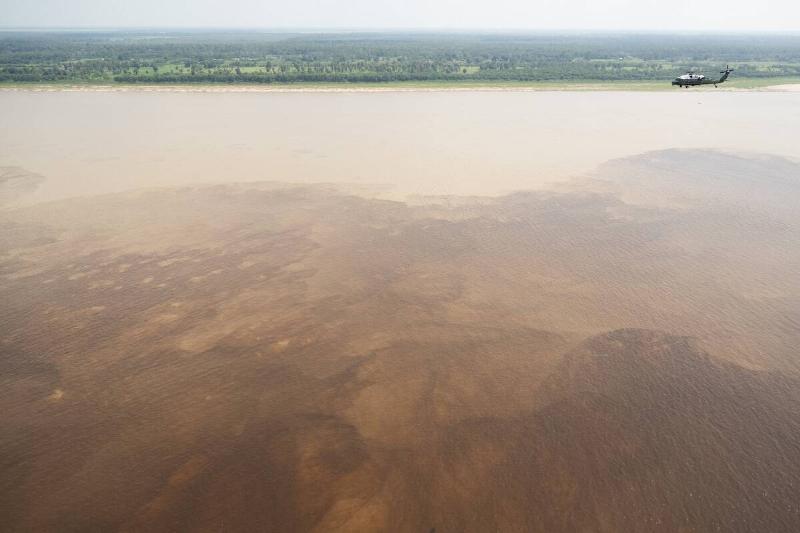 A helicopter flies over the Amazon River. 