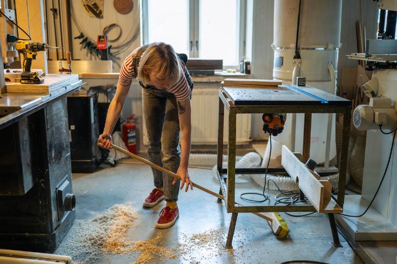 Woman sweeping under workbench.