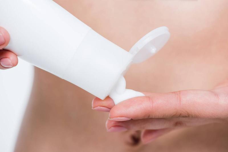 Hands holding lotion bottle.