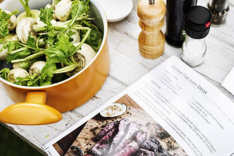 Closeup of white radish in pot next to cook book.