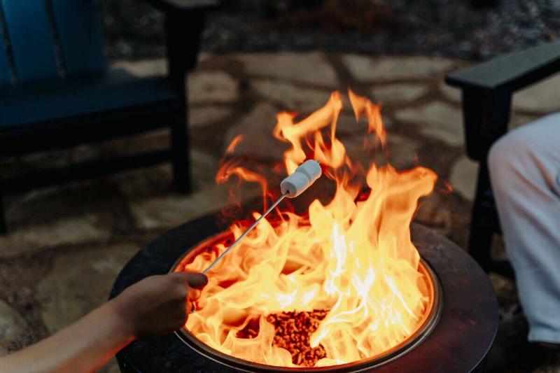 A closeup shot of a person roasting marshmallows over a fire pit.