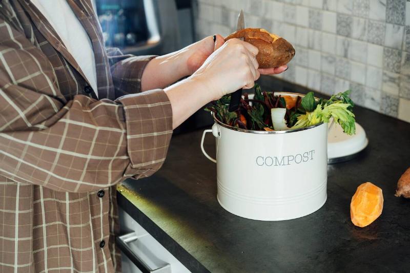 Woman putting vegetables and leftovers into the compost.