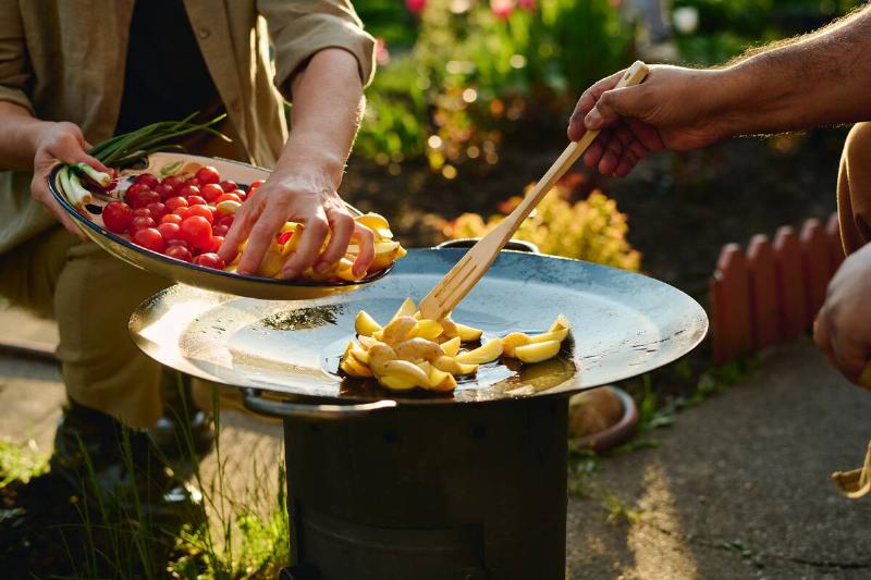 Chopped potatoes frying on outdoor cooking set up. 