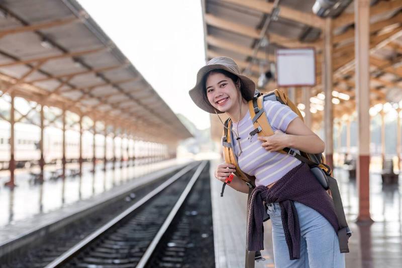 Woman with backpack waiting for train on platform.