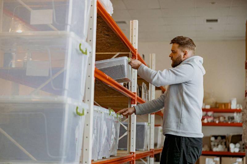 Man looking through clear bins on shelves. 