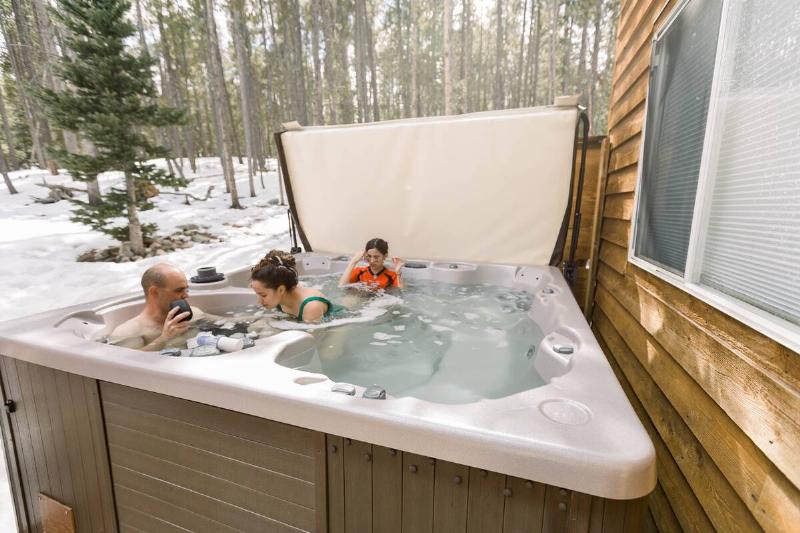 Family in hot tub in winter, snowy landscape. 