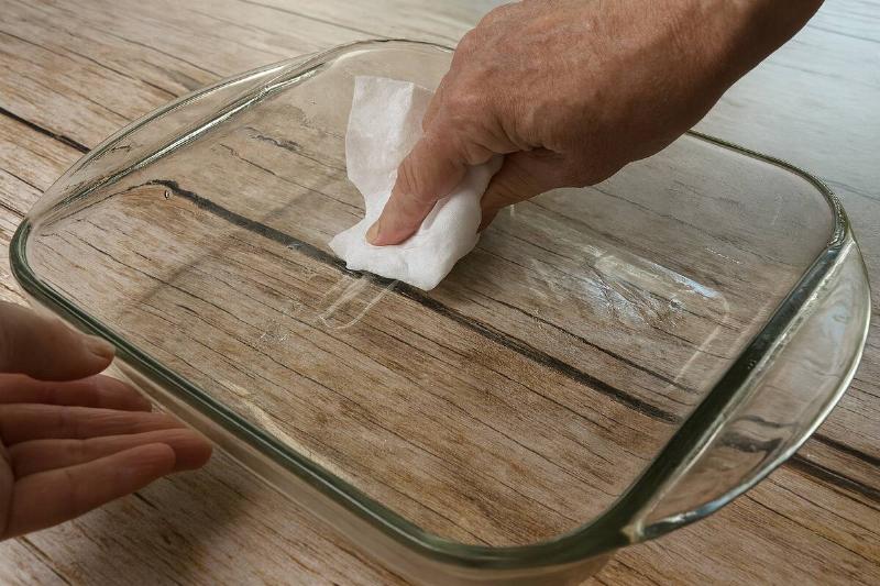Hand wiping glass pan with coffee filter. 
