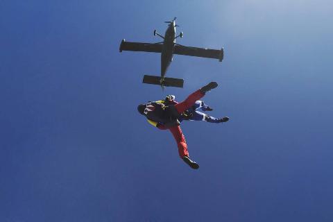 Freeflying skydivers in blue sky.