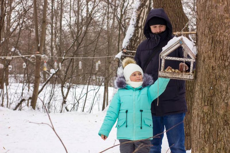 Girl and father feeding birds together. 