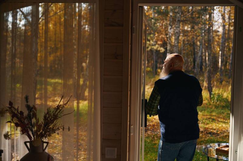 Man admiring autumn forest from his back porch. 