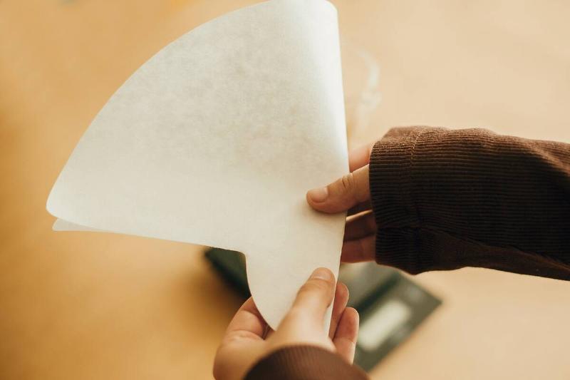 Hands holding paper filter for pour over