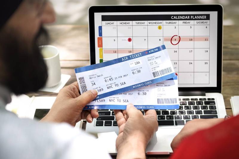 Booking a trip on a computer with physical tickets.