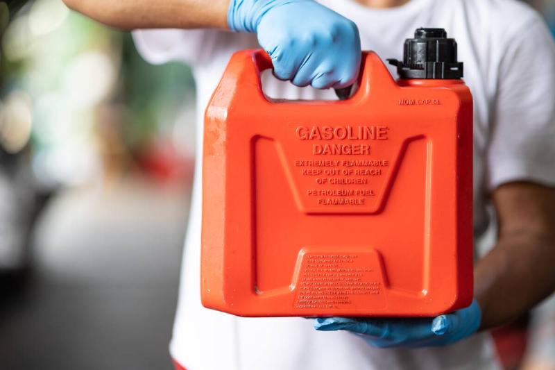 Hands holding red gas container. 