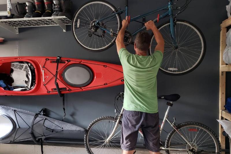 Man putting a bike on a wall mounted hook. 