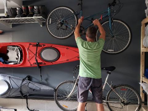 Man putting a bike on a wall mounted hook. 