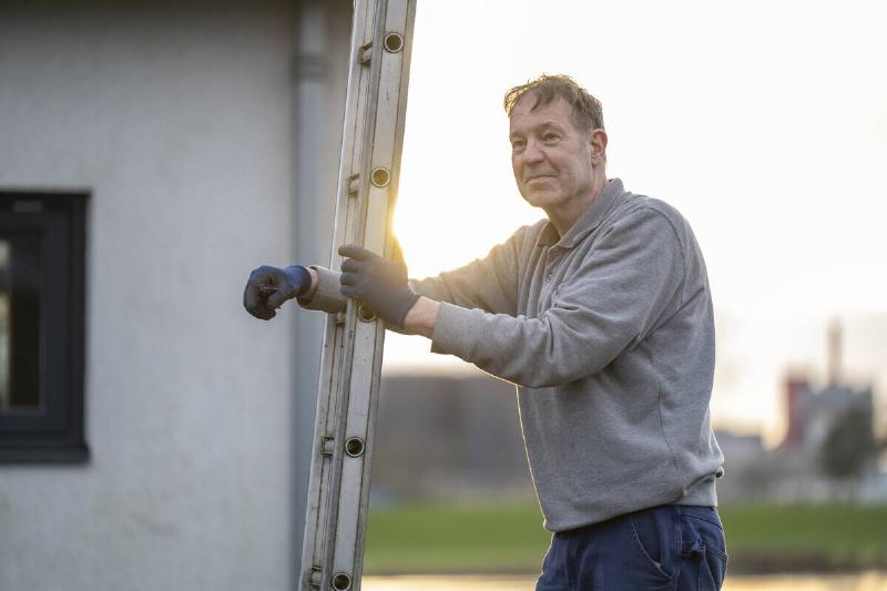 Man standing by a ladder during a golden hour sunset.