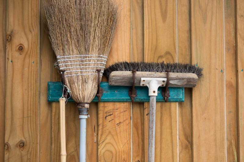 Two brooms mounted on a wall. 