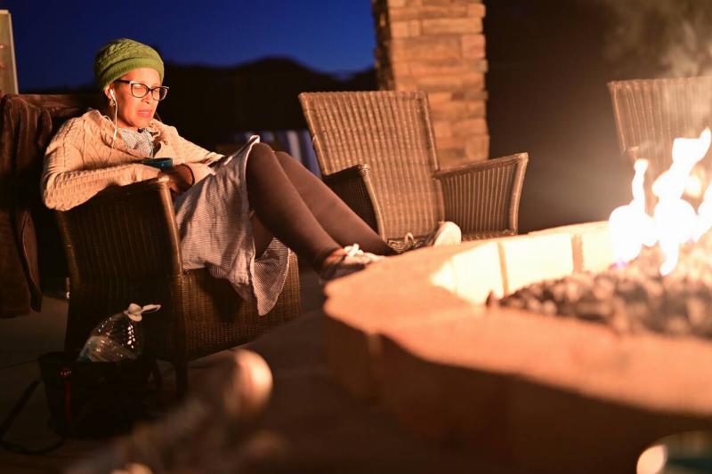 Lady relaxing outside by firepit.