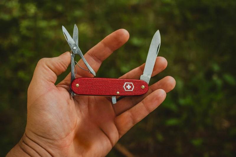A hand holding a Swiss Army knife, showing the scissors.