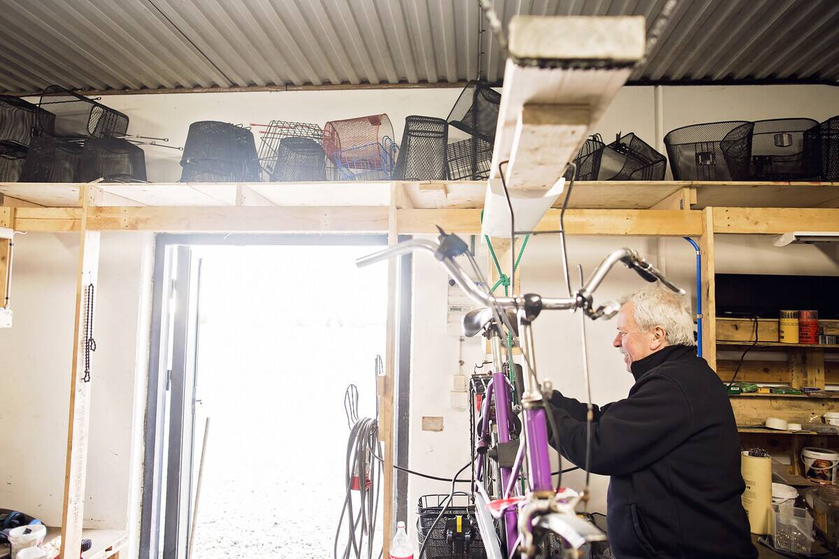 Man working on bike with ceiling storage above. 