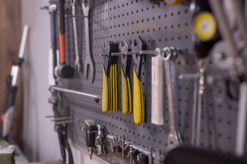 Set of tools, screws, pliers and nuts on a pegboard. 