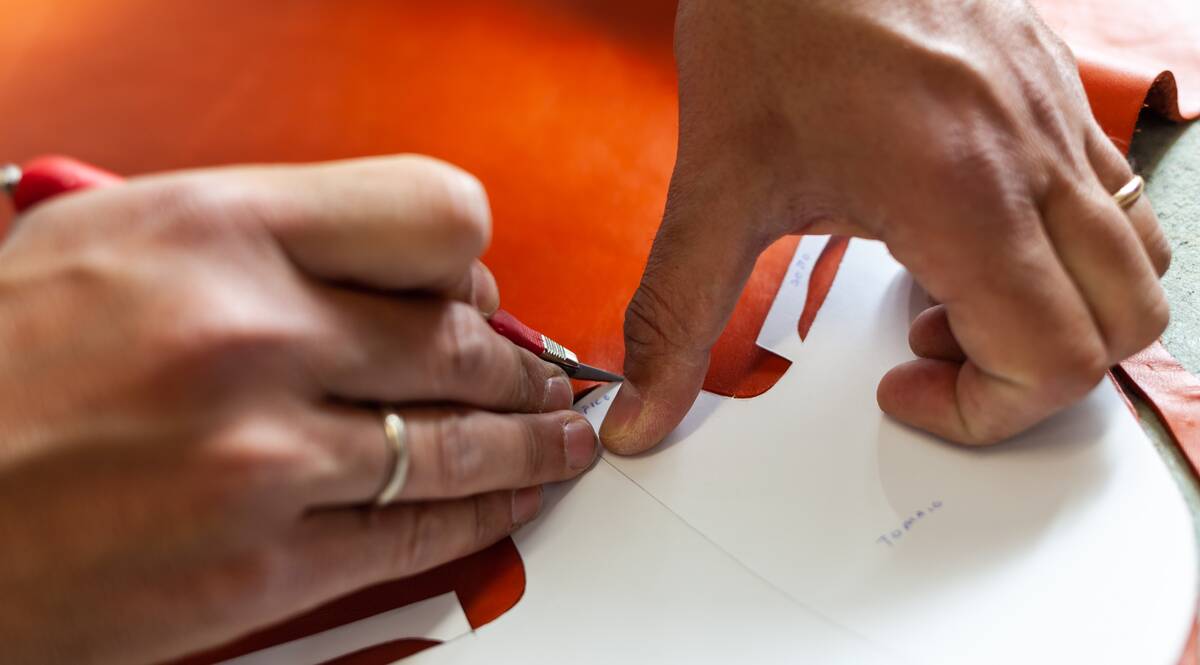 Hands using knife to scrape off sticker. 
