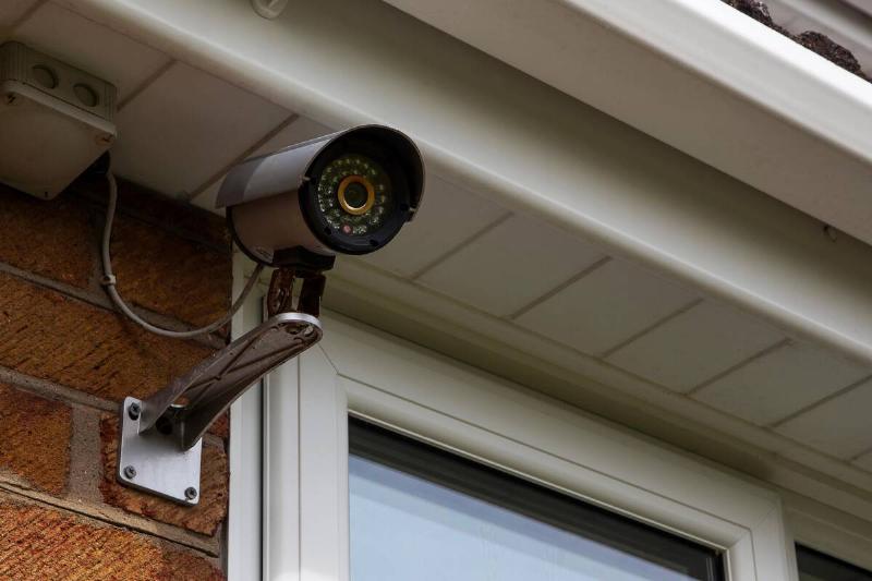 Surveillance camera attached to a brick house.