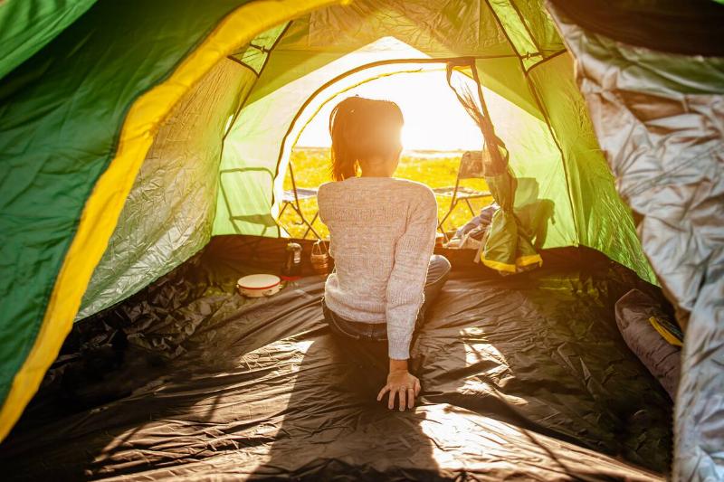 Back of woman in a tent with a blanket on the ground.