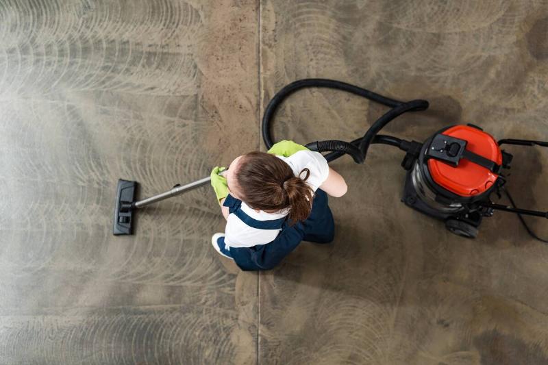 Woman vacuuming floor of garage.