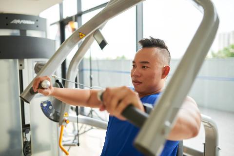 Vietnamese young man having training in gym.