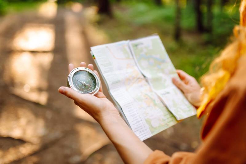 Woman hiking, holding map and compass. 