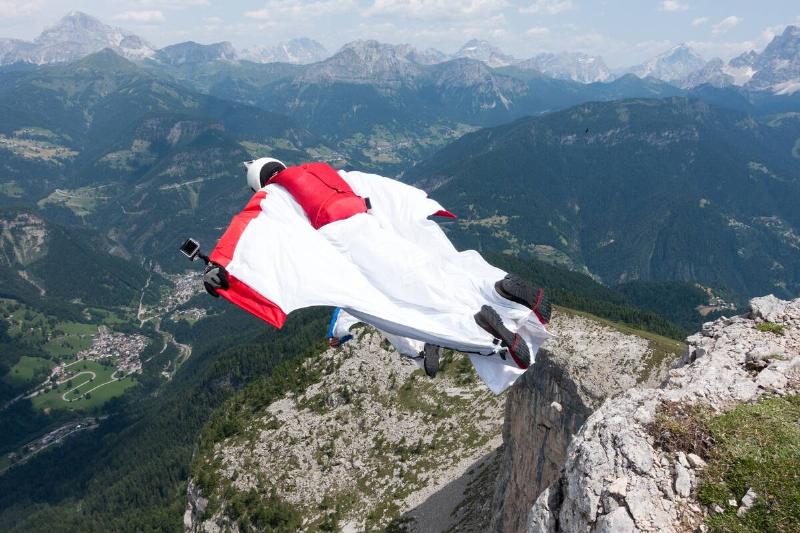 Two male BASE jumpers exiting from mountain top, Dolomites, Italy