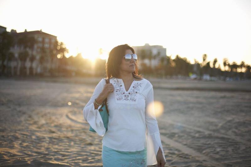 Woman on beach wearing long-sleeve shirt.