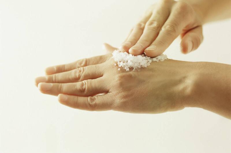 Woman rubbing salt on hand.