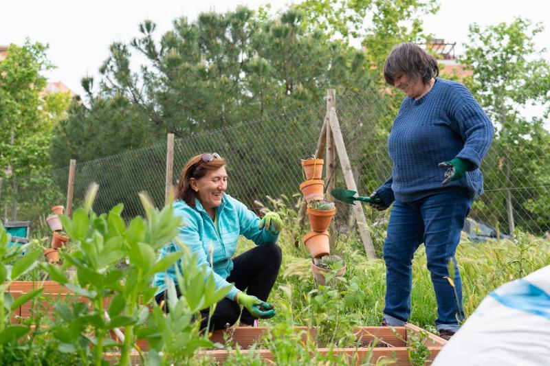 Two women working together in a community garden. 