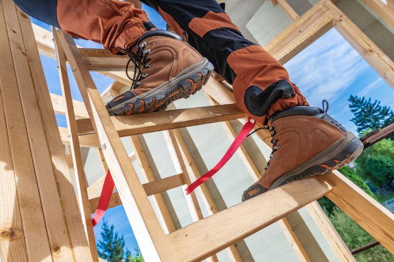 Worker wearing boots and climbing a ladder. 