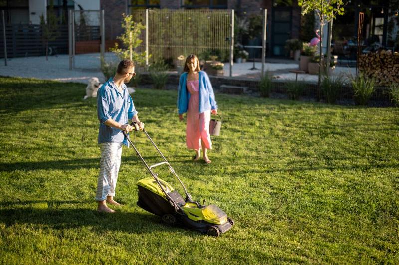 Man mows the lawn with lawn mower.